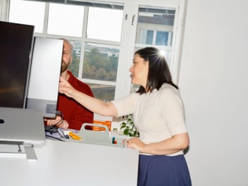 Two Vincit colleagues talking, one pointing at the computer screen